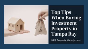 A hand holds a small wooden house while another offers a money bag. Text reads, "Top Tips When Buying Investment Property in Tampa Bay."