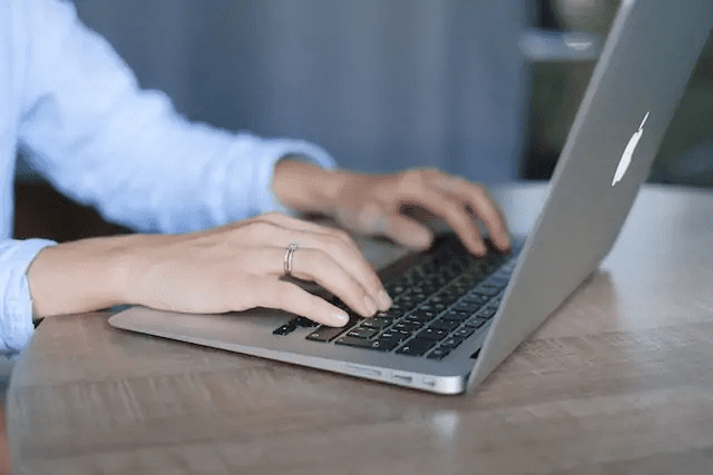 person-in-blue-shirt-writing-on-their-laptop-at-a-desk