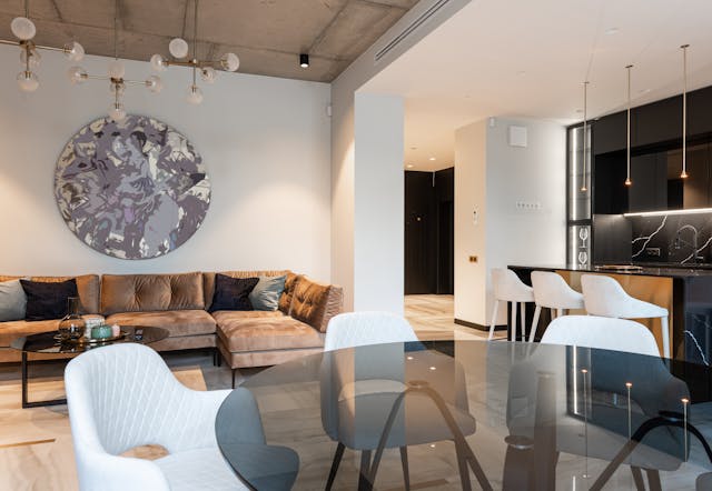 stylish-open-living-space-with-glass-table-velvet-sofa-and-dark-kitchen