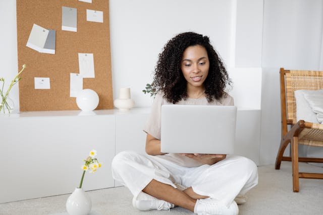 woman-sitting-on-floor-using-laptop-in-bright-minimalist-room
