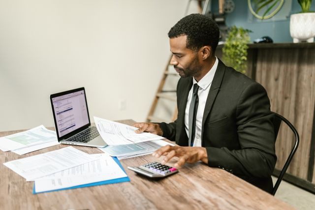person at a desk working on documents with a laptop