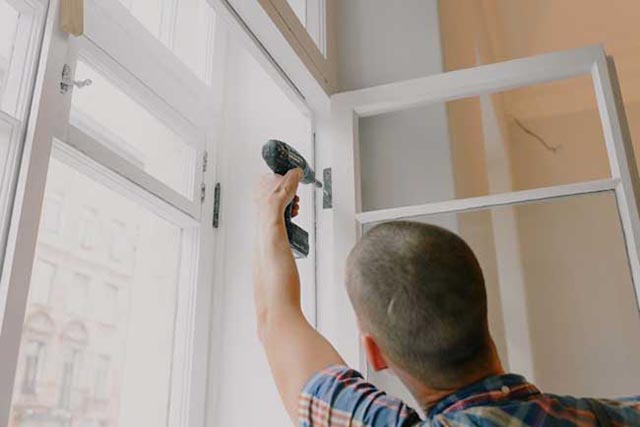 person-holding-a-drill-to-a-window-pane